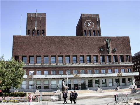Oslo City Hall, red brick facade with clock tower, people walking on the square