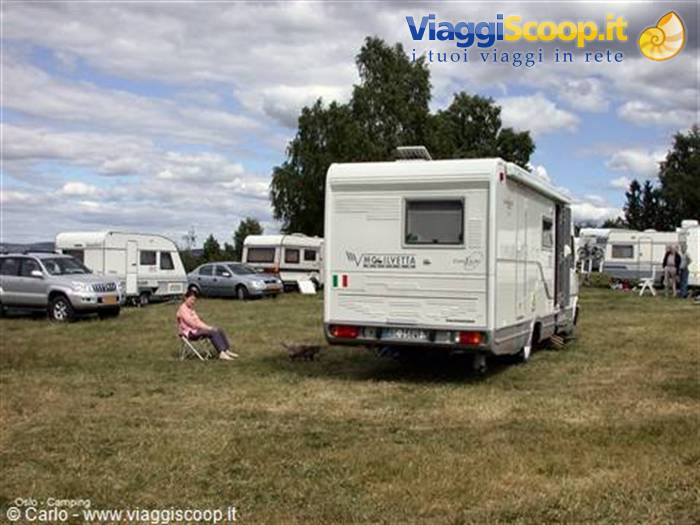 White motorhome and woman sitting at Oslo campsite among caravans and trees