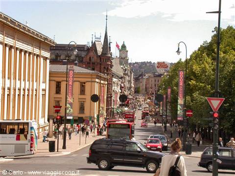 Karl Johans gate in Oslo: traffic and pedestrians among yellow buildings and spires