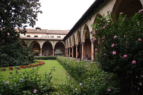 Brick arches of the cloister garden in bloom, Santo Stefano basilica, Bologna