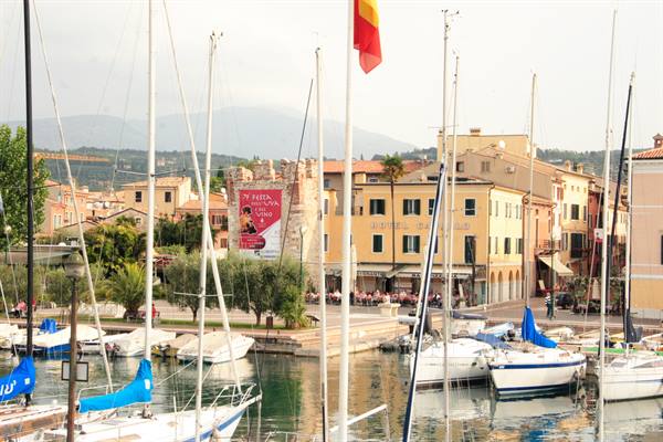 Sailboats moored at the marina in front of Bardolino's colorful buildings