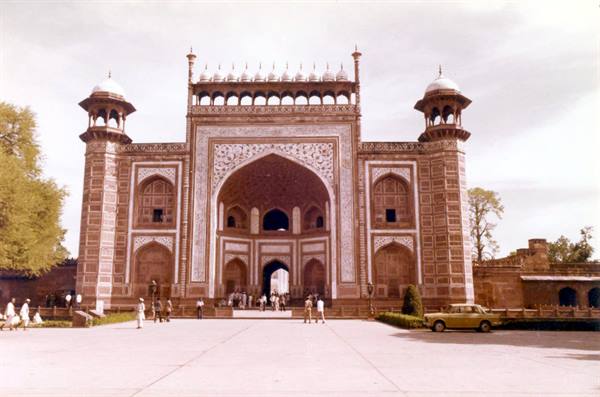 Tourists beneath the grand marble and sandstone gateway of the Taj Mahal, Agra