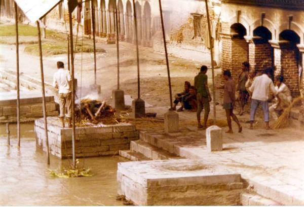 Men near a funeral pyre on stone steps by the river