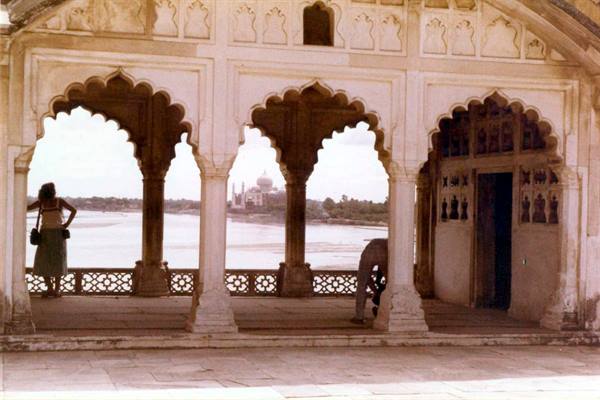 Woman under Agra Fort arches looks at the Taj Mahal across the river