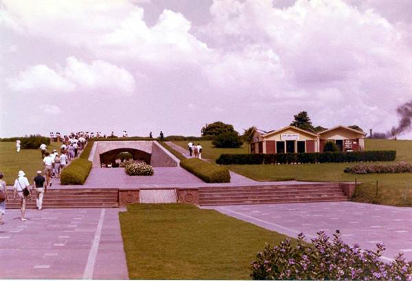Tourists walk toward Raj Ghat memorial among lawns and stone steps