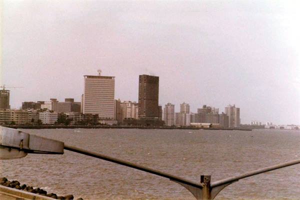 Mumbai skyline from the seafront, metal railing, clear sky over towers