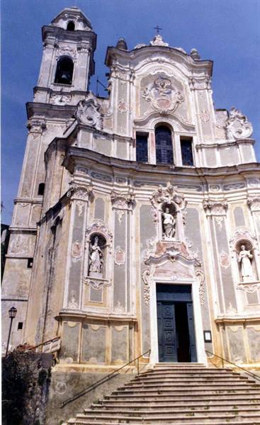 Baroque facade with statues in niches, bell tower and staircase under midday light