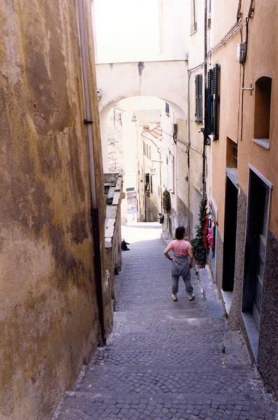 Girl in overalls walking down a cobbled stairway between old houses
