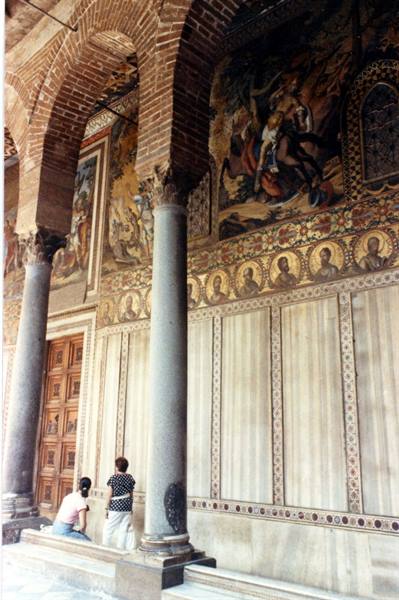 Byzantine mosaics on a basilica facade, two visitors near columns