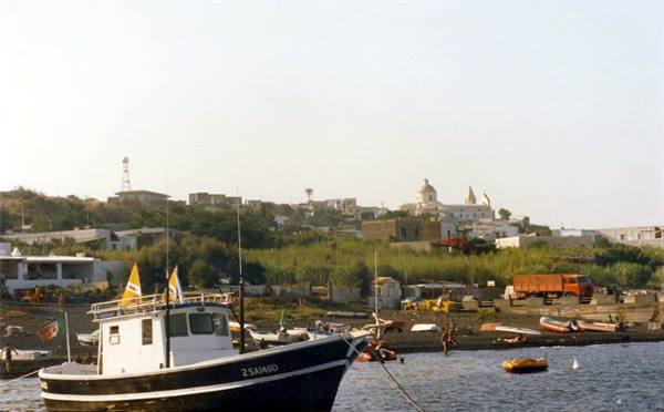 Black and white fishing boat moored, village with domed church in the background