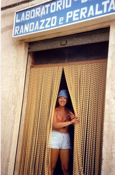 Smiling woman in hat parting bead curtains of the Randazzo e Peralta workshop