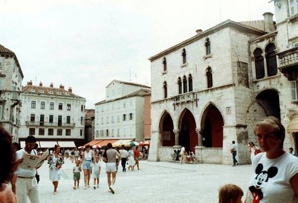 Tourists walk across Split's square in front of the old town hall