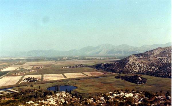 Cultivated fields and small lake among rocky hills, hazy mountains beyond