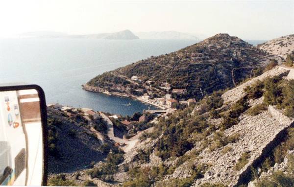 Village on blue bay seen from the bus, side mirror in foreground
