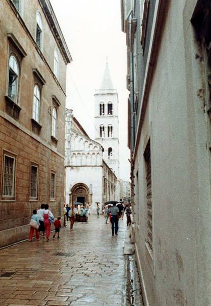 Rain-soaked cobbled street leading to the Romanesque bell tower of Zadar cathedral