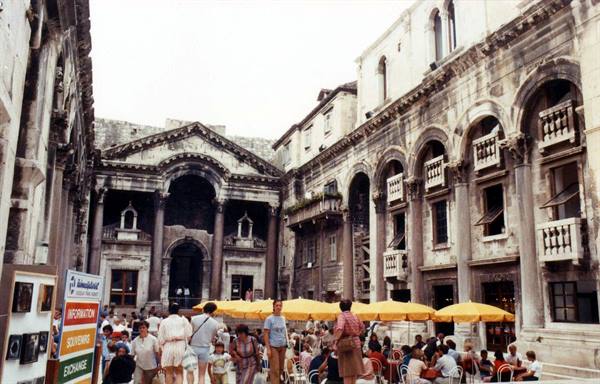 Tourists under yellow umbrellas in Diocletian's Palace peristyle, Split