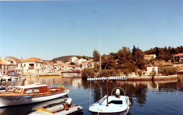 Wooden boats and white fishing boats moored at the harbor, stone houses behind