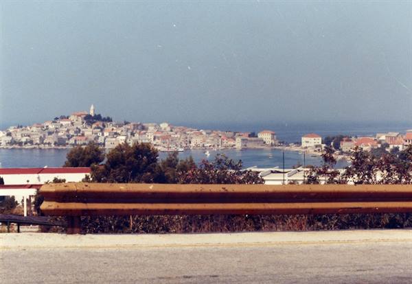 Rusty guardrail in foreground, old town with bell tower across the water