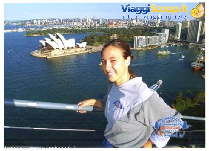 Smiling girl on Sydney Harbour Bridge railing, Opera House and skyscrapers behind