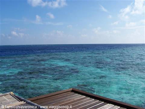 Wooden jetty over turquoise lagoon water beneath a blue sky
