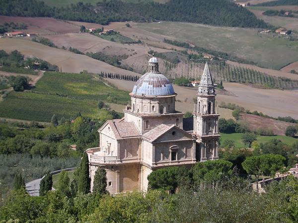 San Biagio church in Montepulciano, grey dome and bell tower among cultivated hills