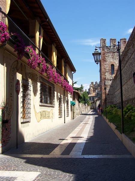 Alley with bougainvillea-filled balconies and old crenellated tower, Marostica