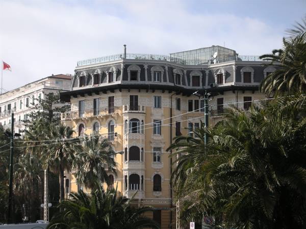 Yellow building with slate roof among palm trees, Sanremo