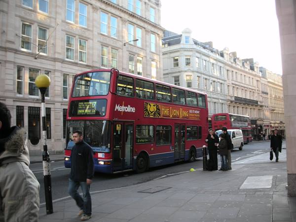 Red Metroline double-decker bus with The Lion King ad on a London street