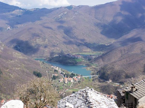 Stone rooftops above Vagli lake and bridge among bare mountains