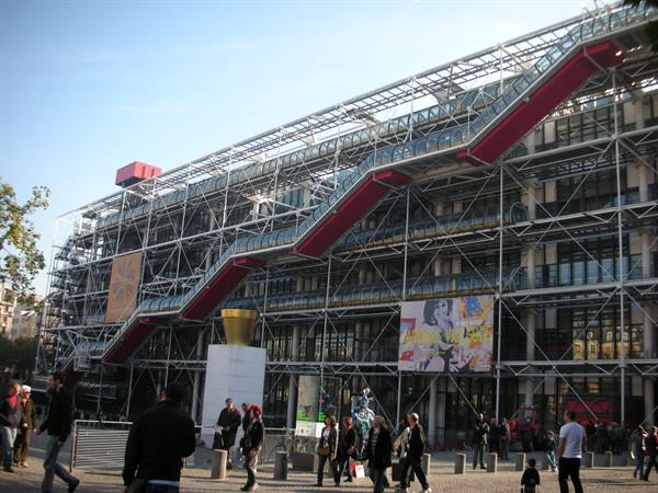 Centre Pompidou in Paris: steel framework with red escalator, tourists walking below