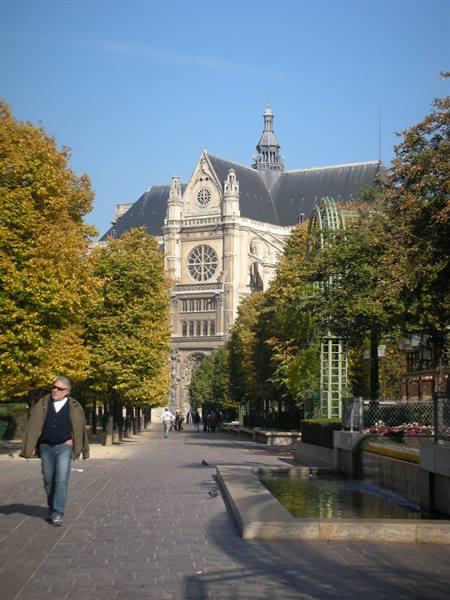 Man strolls among autumn trees toward the Saint-Eustache church in Paris