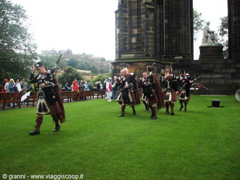 Pipers in kilts playing bagpipes on the lawn by the Scott Monument, Edinburgh