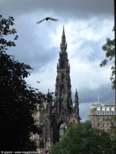 Scott Monument in Edinburgh, Victorian Gothic spire framed by trees under cloudy sky, a bird flying