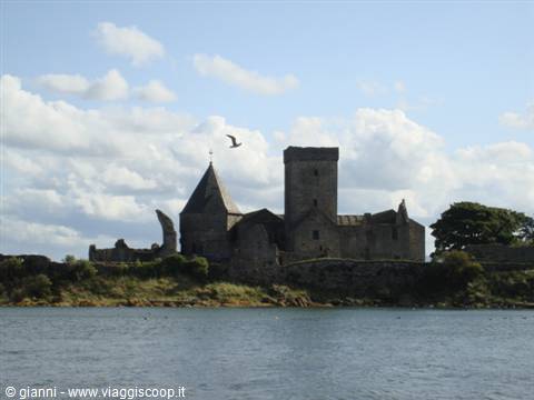 Inchcolm Abbey's grey stone ruins on the island, bird flying, water and clouds
