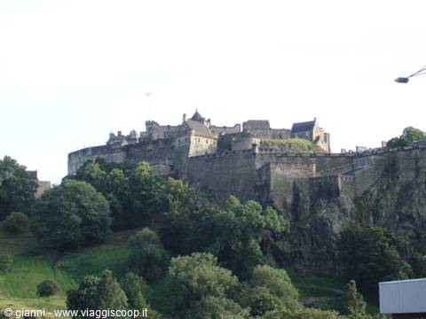 Edinburgh Castle stone fortress atop volcanic rock, surrounded by green trees