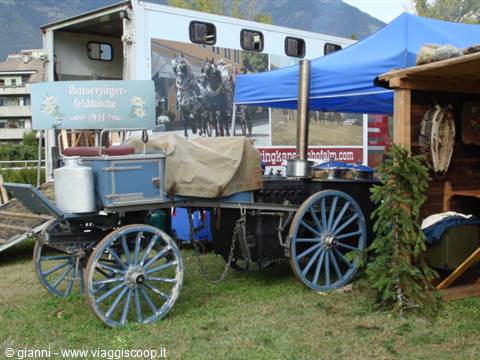 Historic wooden carriage with blue wheels under tent near Münstertaler sign