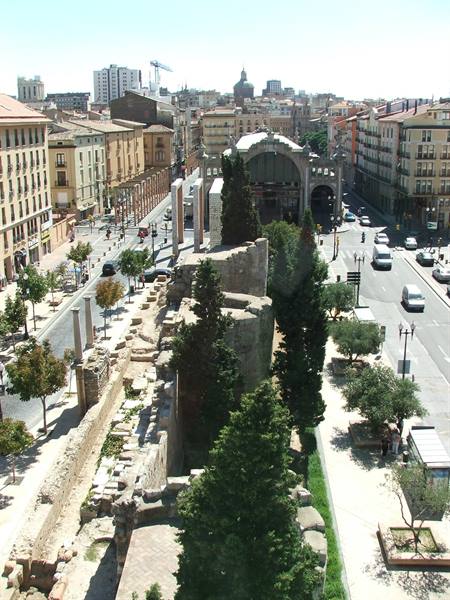 Ancient Roman stone walls with pines beside Zaragoza's Central Market hall