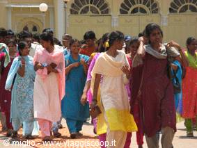 Women in colorful saris walking in front of a yellow building