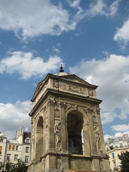 Stone fountain with sculpted figures, Fontaine des Innocents, under cloudy sky