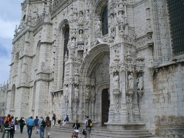 Tourists by the carved stone portal of the Jerónimos Monastery in Lisbon
