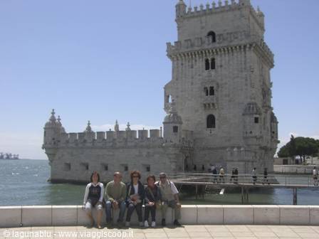 Tourists sitting on the wall in front of Belém Tower, Lisbon