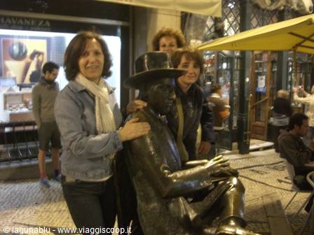 Tourists hugging the bronze statue of Fernando Pessoa in Lisbon