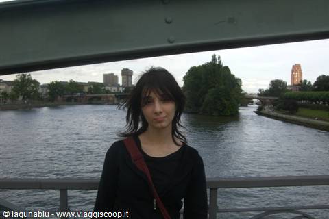 Dark-haired young woman on a steel bridge above a city river