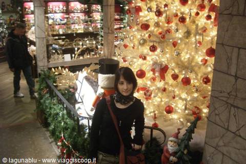Girl beside a white Christmas tree with red ornaments in a shopping mall