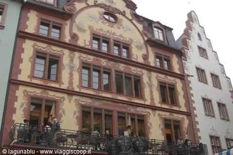 People sitting at a café under the painted yellow and red facade in Mainz
