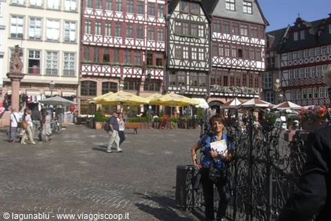 Woman beside an iron fence in front of Römerberg half-timbered houses