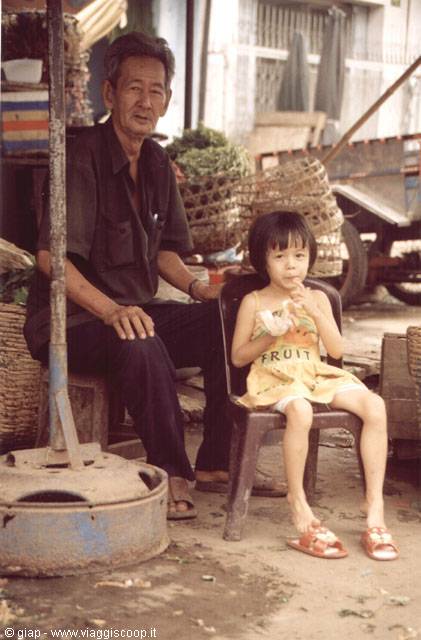Grandfather and little girl sitting in front of woven market baskets