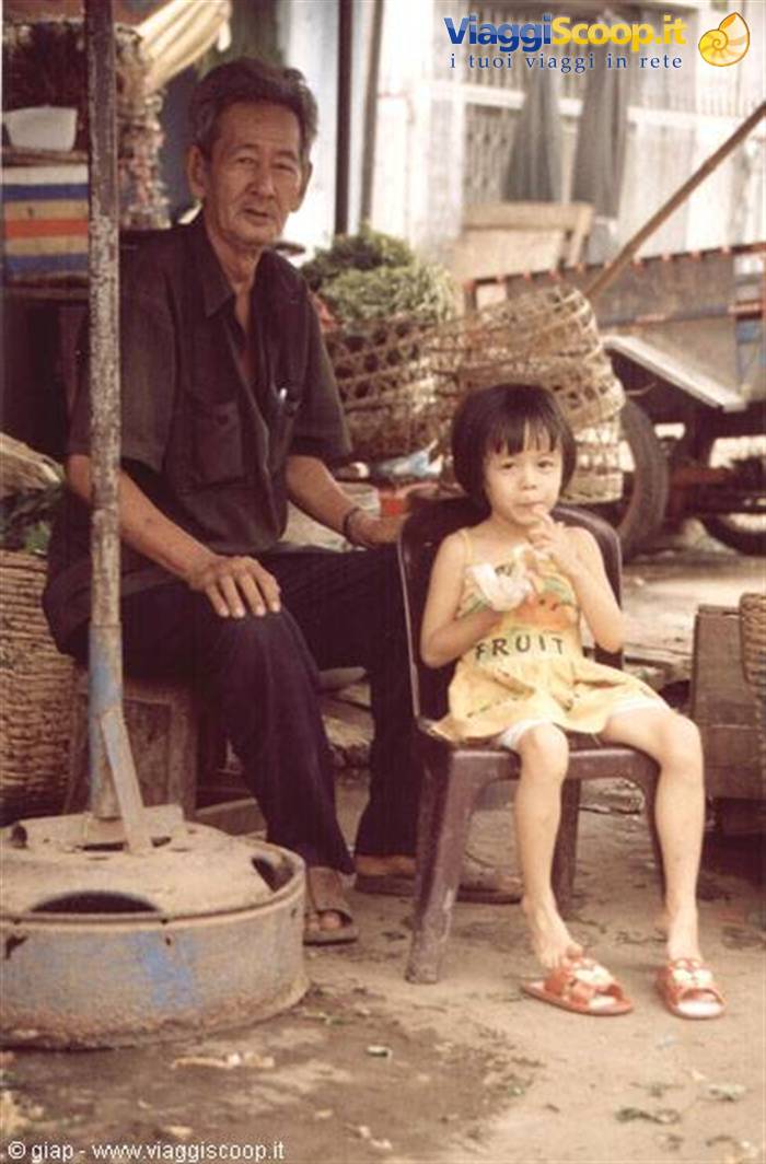 Grandfather and little girl sitting in front of woven market baskets