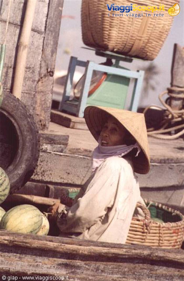 Woman in straw hat selling watermelons from a wooden boat