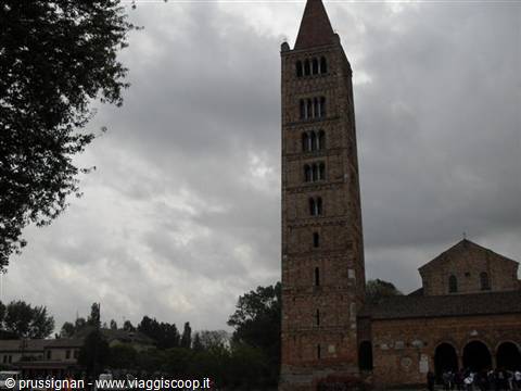 Brick bell tower of Pomposa Abbey under a cloudy sky